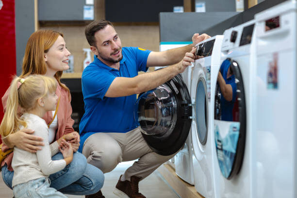 A friendly salesman shows a family the features of a washing machine in an appliance store, showcasing modern design and functionality, while the family attentively listens and discusses their options.